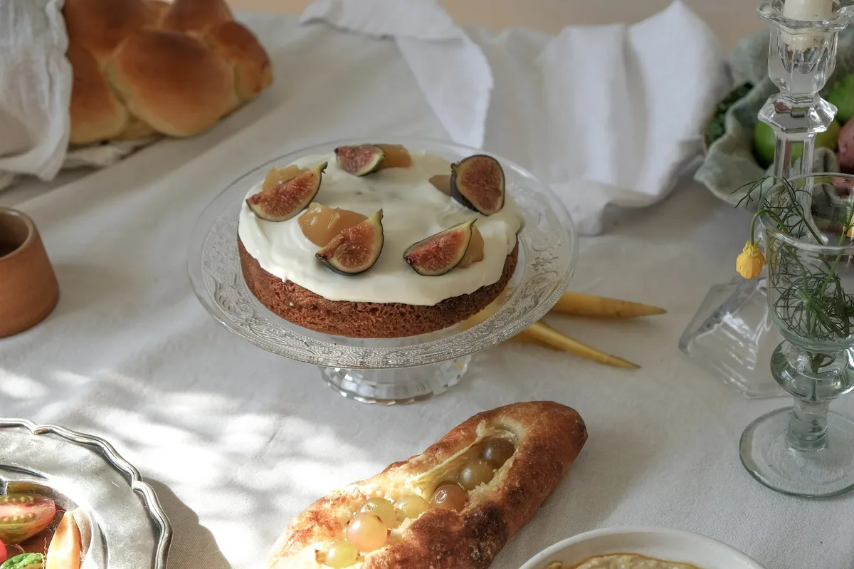 A dessert table with a fig cake, challah and small plates